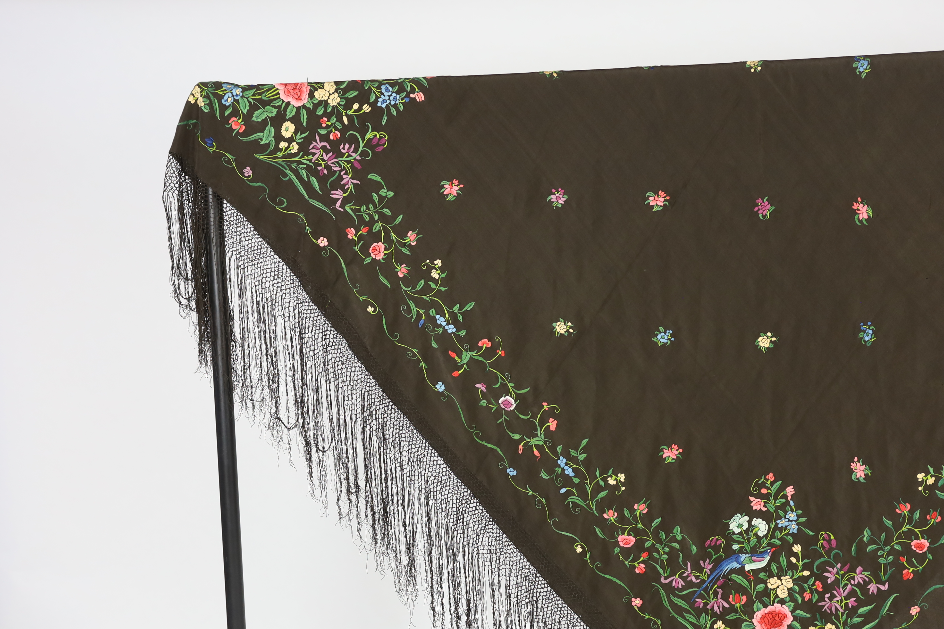 A Chinese silk shawl, circa 1900, embroidered with polychrome threads with birds and flowers against a black silk ground, 164cm sq.